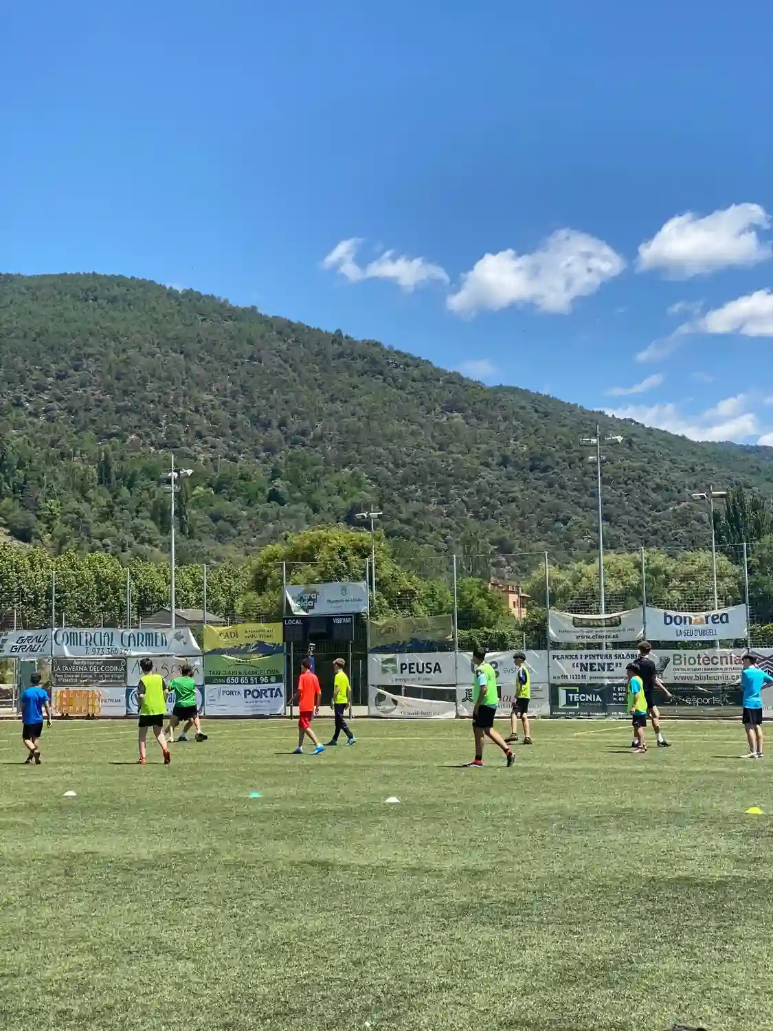 Niños y niñas entrenando en el campo, con la montaña de fondo